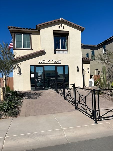 A welcoming, Mediterranean-style community center with a paved entrance and "Welcome" signage.