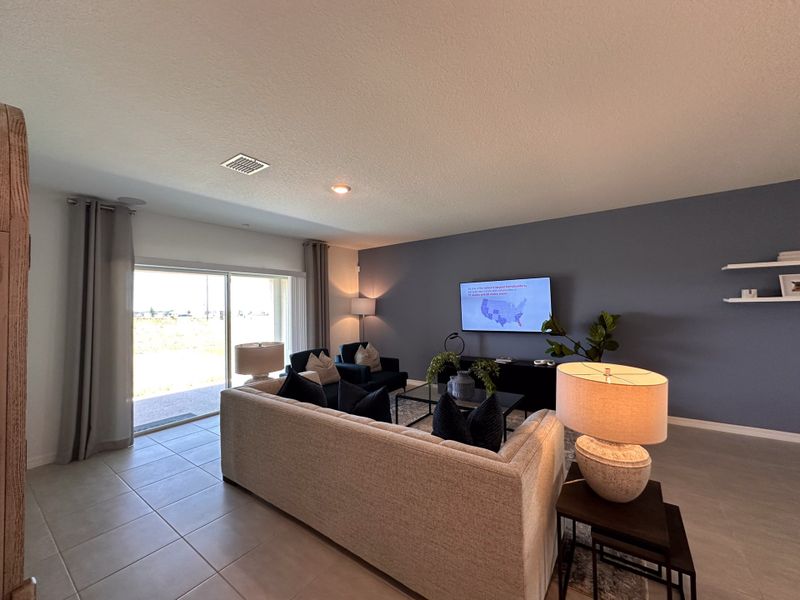 A modern living room featuring a cozy sofa, blue accent wall, and sleek decor, illuminated by natural light.