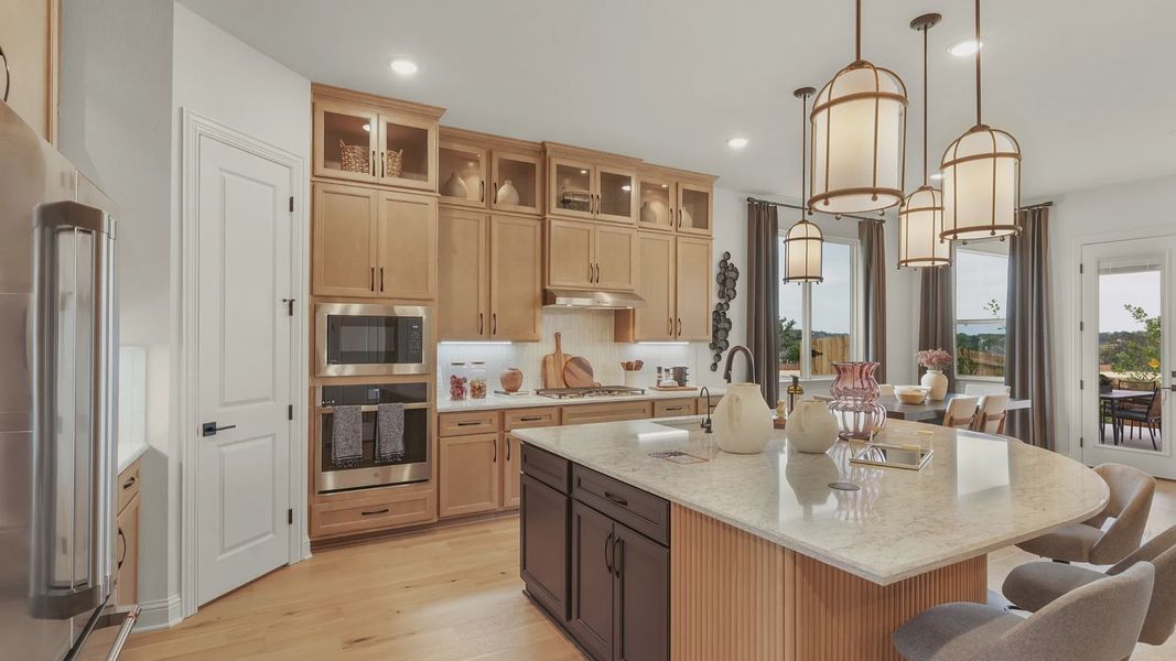 Modern kitchen with ceiling-height cabinets, built-in appliances, statement lighting, and a large center island.