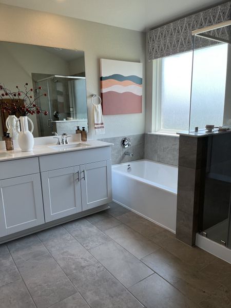 A modern bathroom features a sleek vanity, abstract wall art, spacious bathtub, and large mirror for a stylish look.