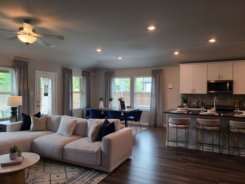 A spacious living area with a cozy sectional, sleek kitchen, and elegant dining, featuring large windows and stylish accents.