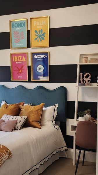 A vibrant bedroom with a bold striped accent wall, colorful decor, and a plush headboard, creating a fun and lively space.