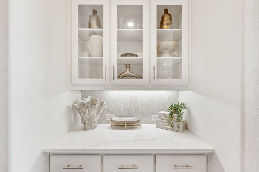 White butler's pantry with glass-front cabinets, quartz countertop, herringbone tile backsplash, and decorative vases White butler's pantry with glass-front cabinets, quartz countertop, herringbone tile backsplash, and decorative vases