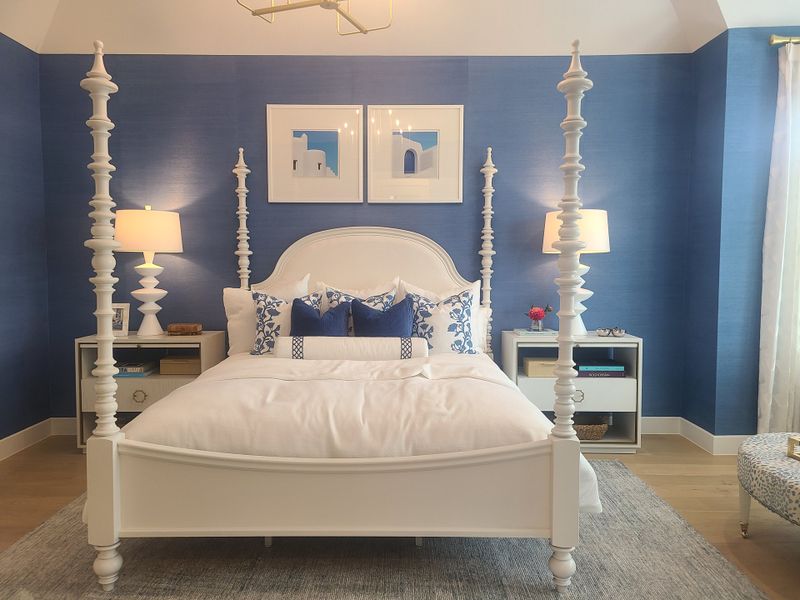 A luxurious bedroom featuring a four-poster bed, elegant blue accent walls, and chic decor elements.