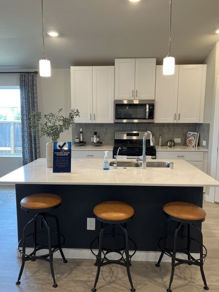 A modern kitchen featuring a spacious island, elegant pendant lights, and sleek white cabinetry.