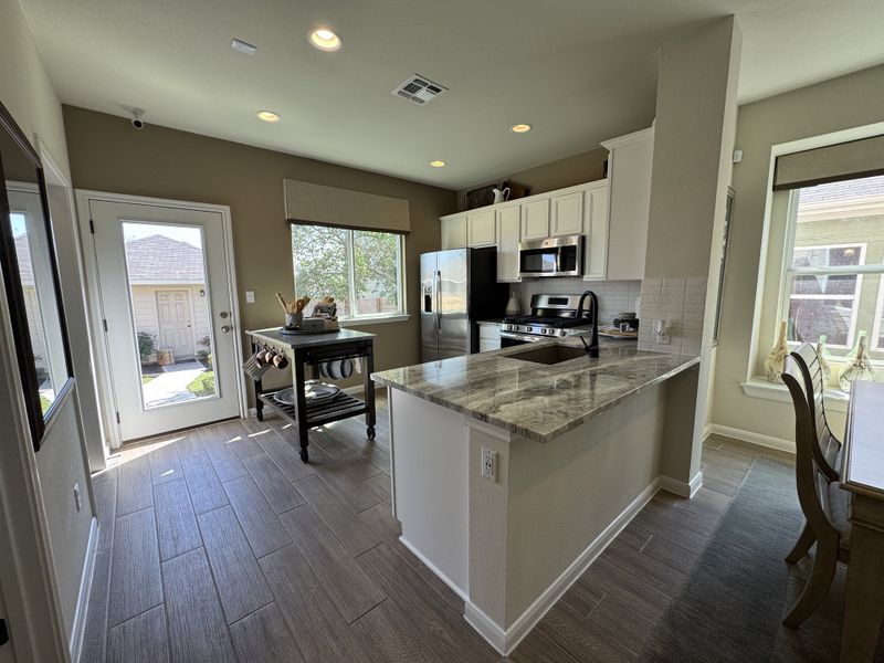 A bright kitchen featuring a marble countertop, stainless steel appliances, and a cozy dining nook with ample natural light. A bright kitchen featuring a marble countertop, stainless steel appliances, and a cozy dining nook with ample natural light.