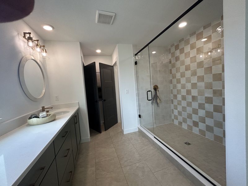 A modern bathroom with a checkered tile shower, sleek vanity, and contemporary lighting.
