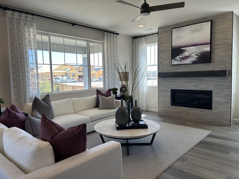 A contemporary living room with elegant decor, a sleek fireplace, and a large window offering natural light.