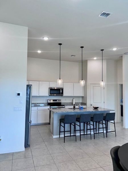 Modern kitchen with sleek white cabinets, stainless steel appliances, and a spacious island with stylish pendant lighting.
