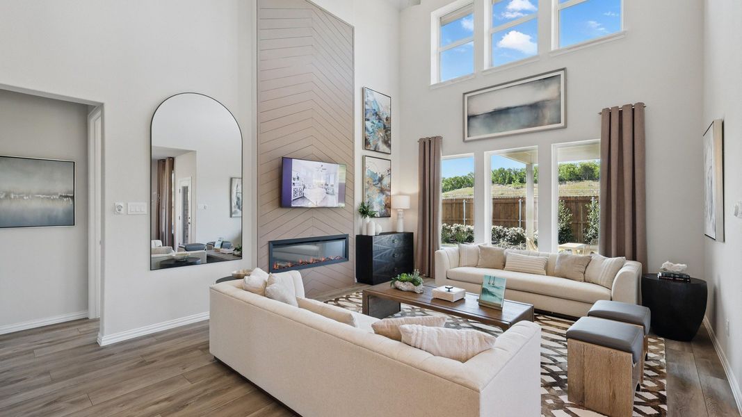Open-concept living room featuring soaring ceilings, expansive windows, and a modern fireplace feature wall. Open-concept living room featuring soaring ceilings, expansive windows, and a modern fireplace feature wall.