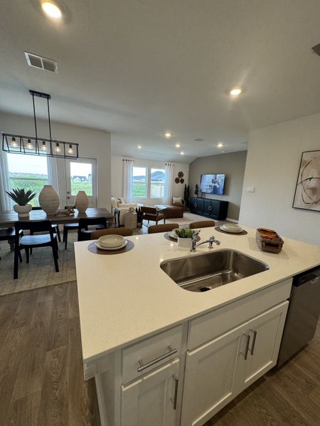 Open-concept kitchen and living area with sleek countertops, modern lighting, and warm wood flooring. Open-concept kitchen and living area with sleek countertops, modern lighting, and warm wood flooring.