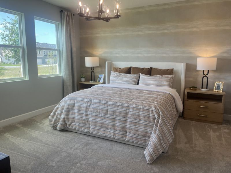 A serene bedroom with a plush bed, modern striped bedding, rich wooden nightstands, and ambient lighting.