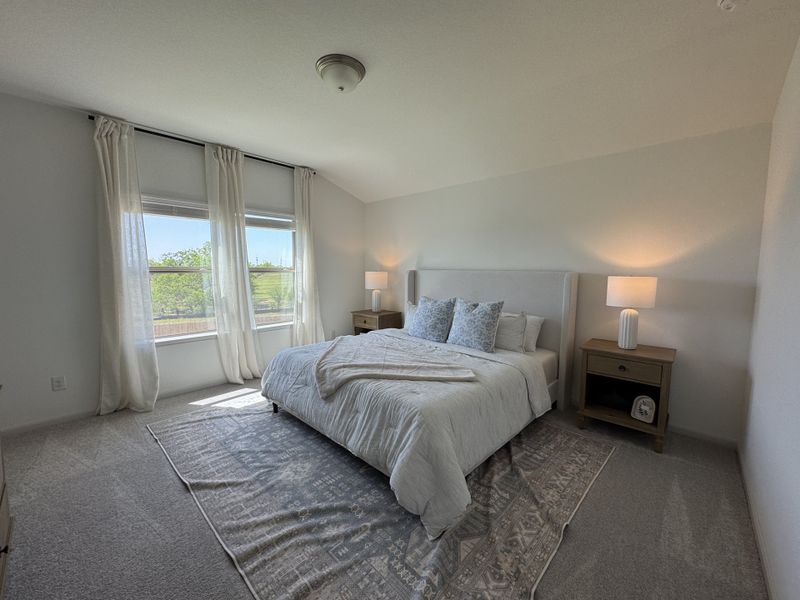 A serene bedroom with soft lighting, plush bedding, and large windows offering a view of greenery outside. A serene bedroom with soft lighting, plush bedding, and large windows offering a view of greenery outside.