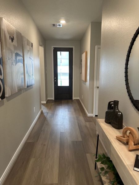 A modern hallway with wood flooring, abstract art, and sleek decor, leading to a stylish entrance. A modern hallway with wood flooring, abstract art, and sleek decor, leading to a stylish entrance.