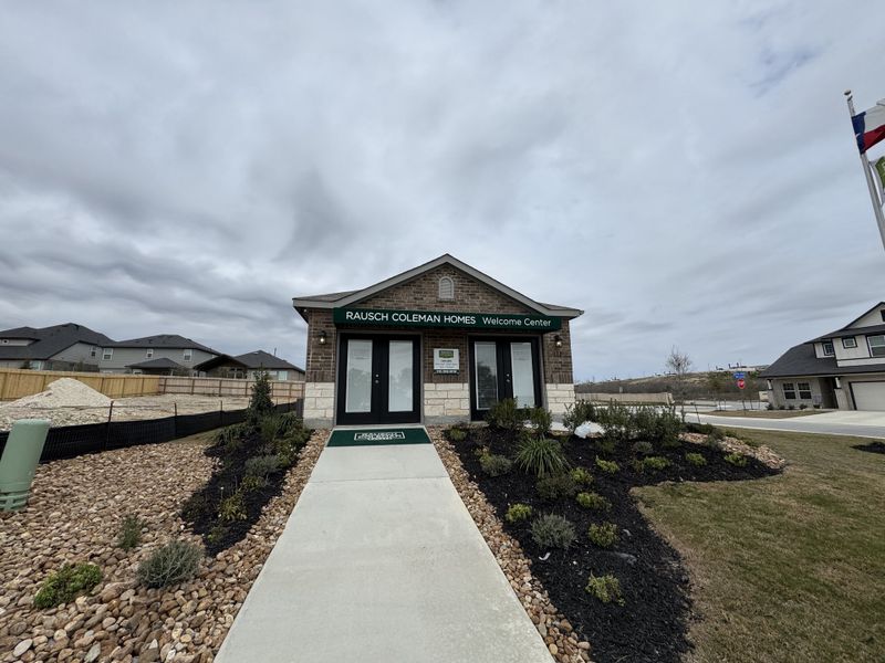 A welcoming center with landscaped entrance at Hunters Ranch by Rausch Coleman Homes (San Antonio, TX).