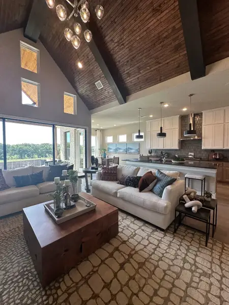 A cozy living area with vaulted ceilings, a rustic chandelier, and modern decor, flowing into an open kitchen space. A cozy living area with vaulted ceilings, a rustic chandelier, and modern decor, flowing into an open kitchen space.