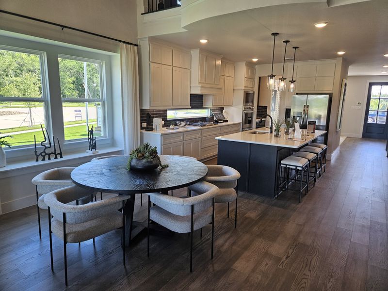 A modern kitchen and dining space featuring sleek black accents, plush seating, and elegant lighting. A modern kitchen and dining space featuring sleek black accents, plush seating, and elegant lighting.
