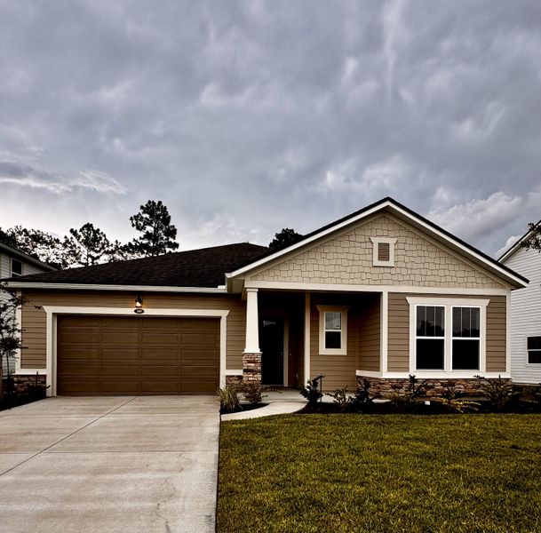 A charming brown home with stone accents and manicured lawn in RiverTown - Ravines by Mattamy Homes (St. Johns, FL).