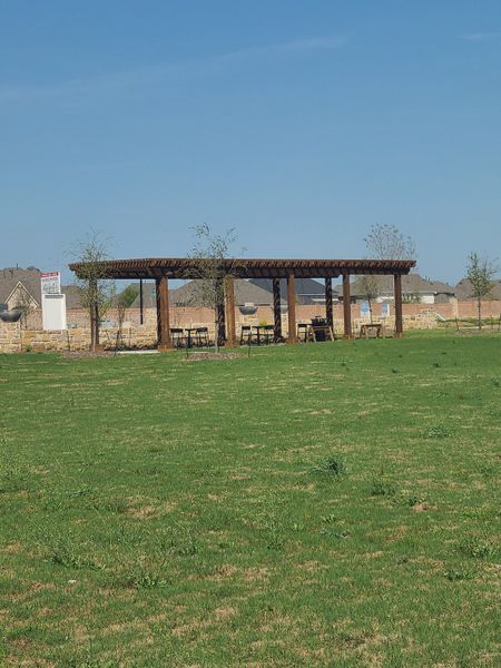 A charming pergola amidst a vast green space in Hazelwood by CB JENI Homes, Frisco, TX. Perfect for outdoor gatherings.