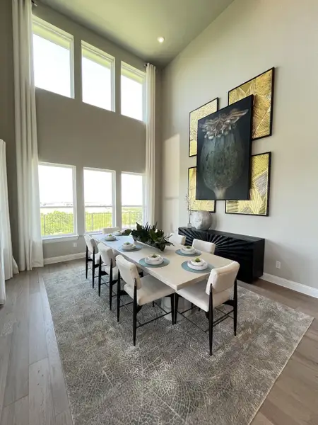 A chic dining room with soaring windows, elegant artwork, and a stylish rectangular table set for eight. A chic dining room with soaring windows, elegant artwork, and a stylish rectangular table set for eight.
