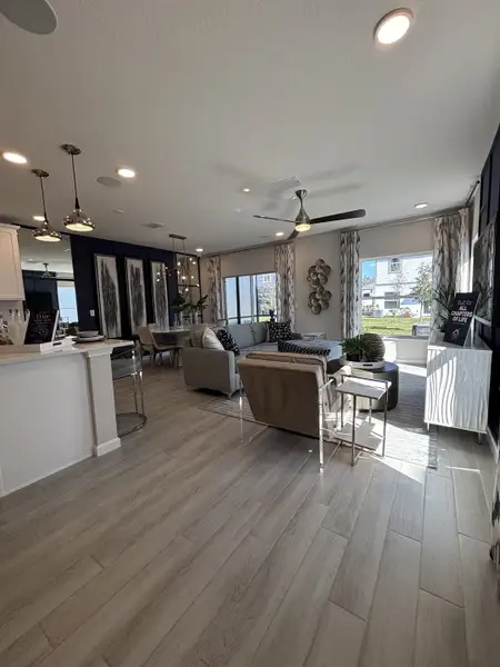 A sophisticated living room with a coffered ceiling, stylish lighting, and plush seating in Eden at Crossprairie by M/I Homes (St. Cloud, FL).