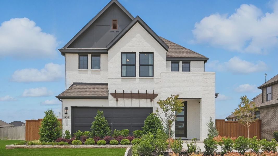 Elegant white brick facade with striking black trim in Westridge. Beautifully landscaped with vibrant greenery.