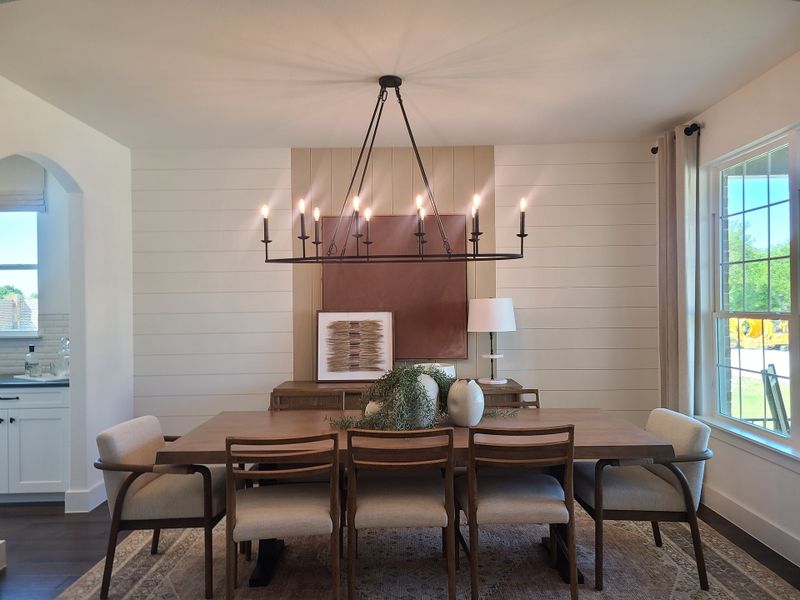 A contemporary dining area featuring a wooden table, elegant chandelier, and large window for natural light. A contemporary dining area featuring a wooden table, elegant chandelier, and large window for natural light.