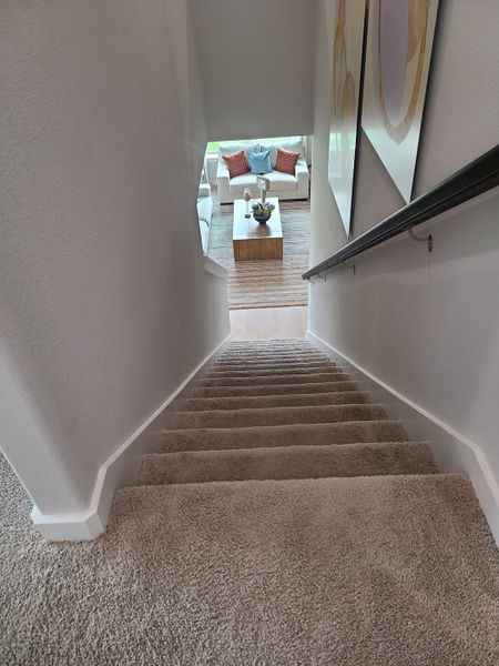A cozy staircase with carpeted steps leading to a bright living area with a modern sofa and stylish decor.