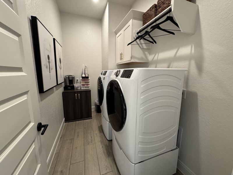 A modern laundry room with sleek appliances, decorative artwork, and practical storage solutions. A modern laundry room with sleek appliances, decorative artwork, and practical storage solutions.