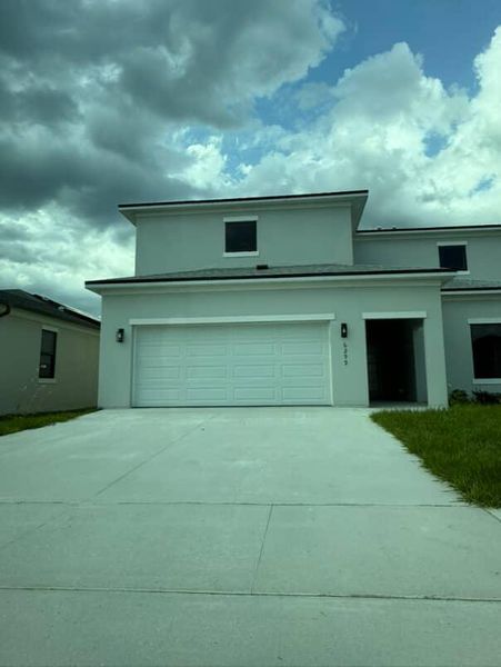 A modern home with a sleek facade and spacious driveway in On Villa Pass by Onx Homes (Mascotte, FL).
