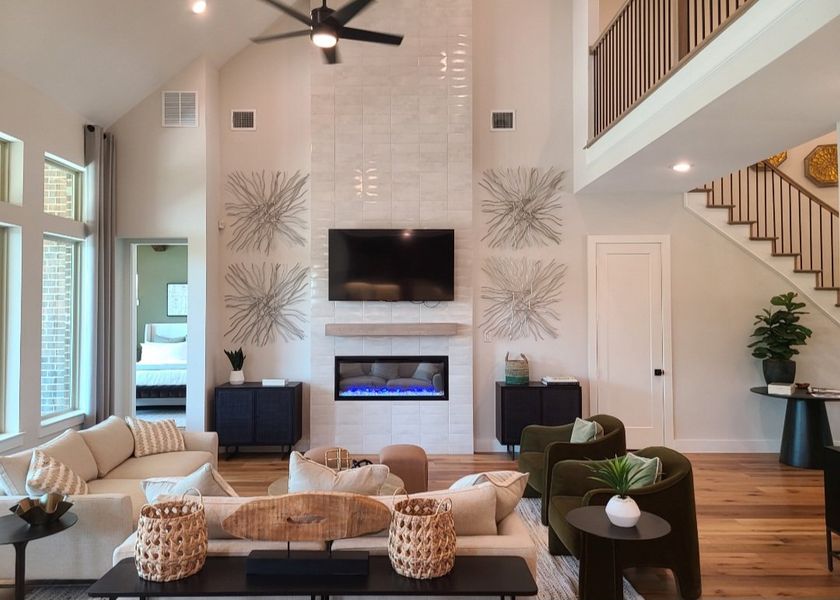 A modern living room featuring high ceilings, elegant decor, and a cozy fireplace beneath a mounted TV. A modern living room featuring high ceilings, elegant decor, and a cozy fireplace beneath a mounted TV.