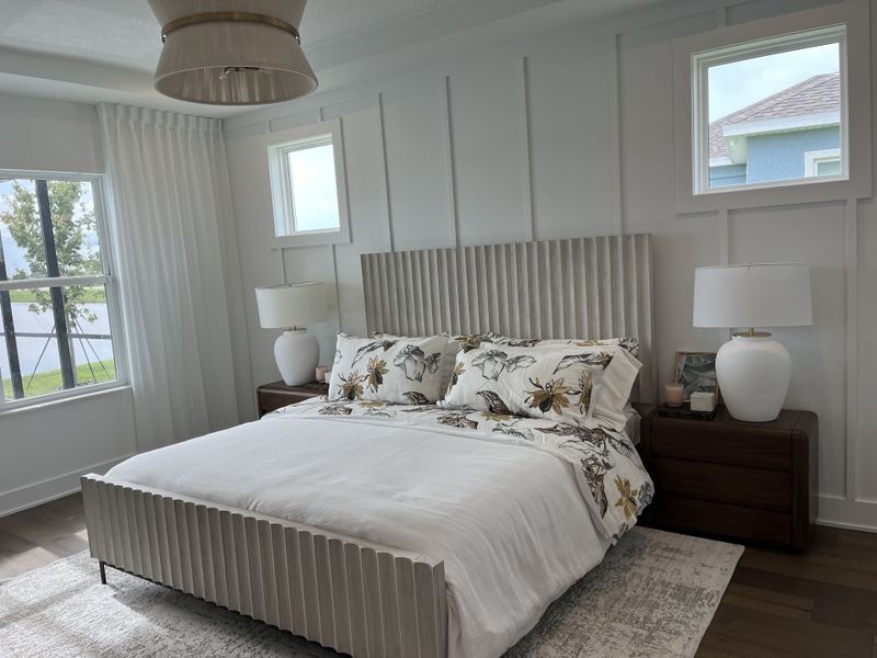 A serene bedroom with a subtle paneled accent wall, elegant bed frame, floral bedding, and stylish bedside lamps.