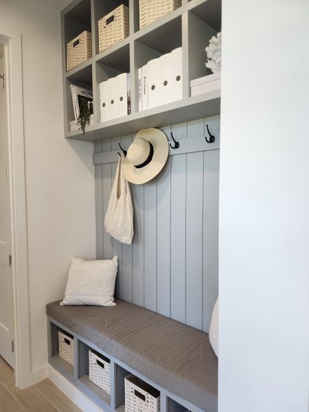 A cozy mudroom bench with baskets, hooks, and upper shelving for organized storage and decor.