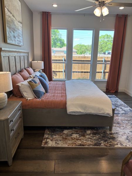 A cozy bedroom featuring a wooden bed, stylish bedding, and large windows with serene outdoor views.