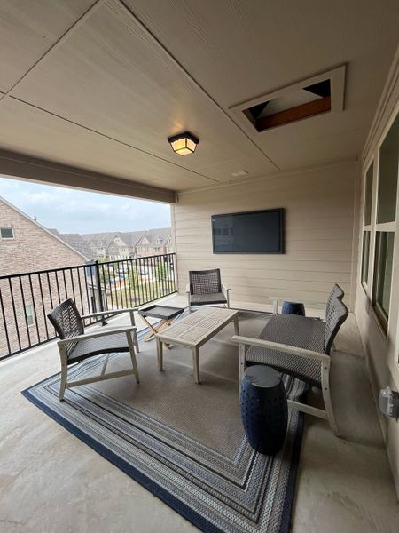 Cozy covered patio with seating, a modern outdoor rug, and a wall-mounted TV, perfect for relaxing and entertaining.