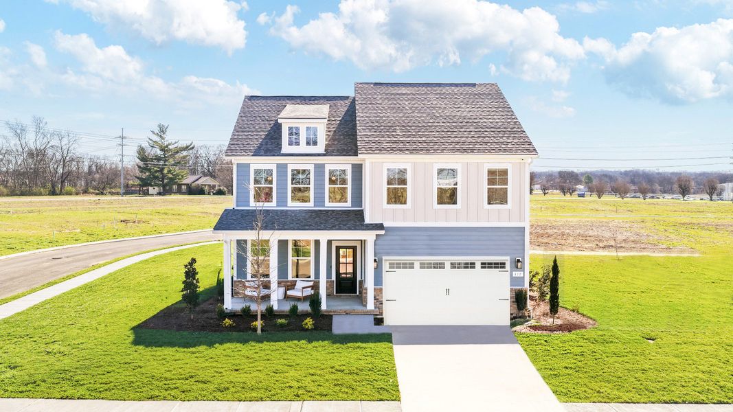 Exterior of home with blue siding and brick accents, with covered front porch and second floor balcony