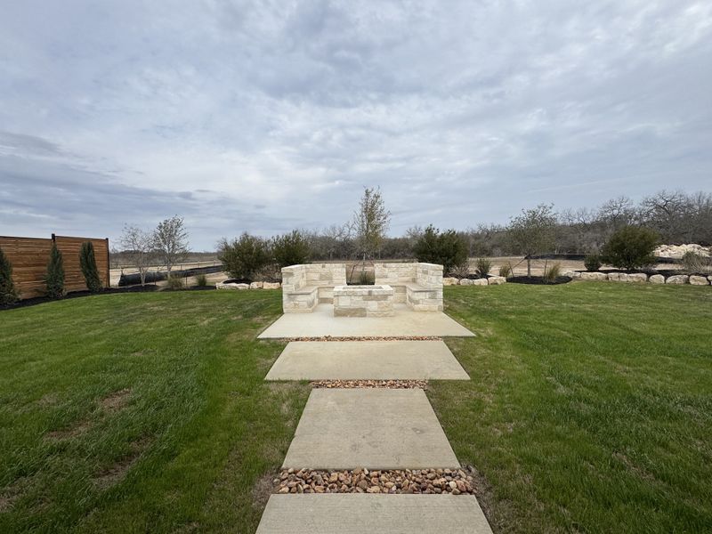 A serene backyard with lush grass and a stone fire pit area in Megan's Landing Half Acre by Perry Homes (San Antonio, TX). A serene backyard with lush grass and a stone fire pit area in Megan's Landing Half Acre by Perry Homes (San Antonio, TX).