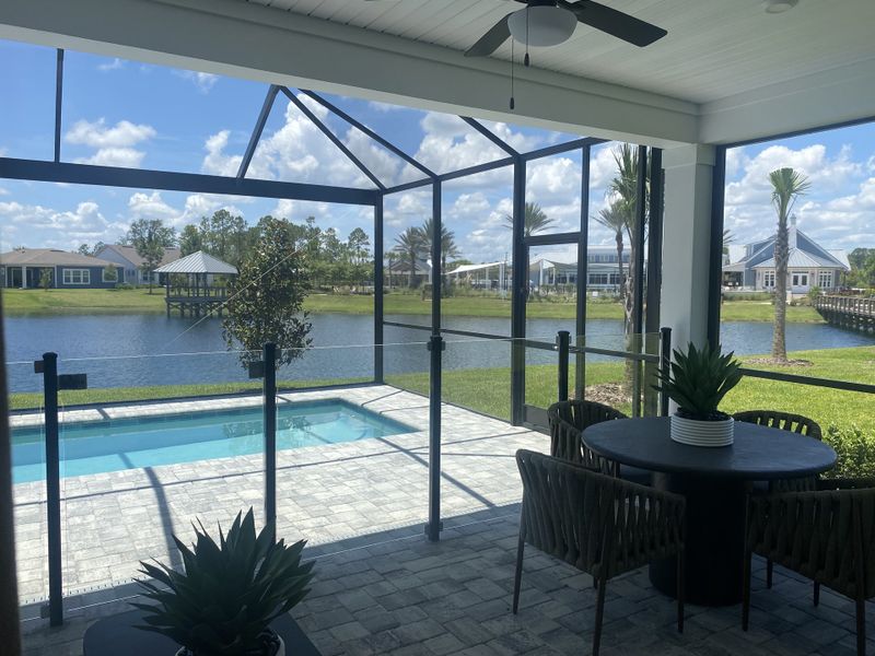 A screened patio with a pool, wicker dining set, and scenic lake views, perfect for relaxing afternoons. A screened patio with a pool, wicker dining set, and scenic lake views, perfect for relaxing afternoons.