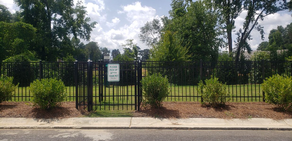 A serene, gated dog park with lush greenery in Chestnut Grove by Starlight Homes (Douglasville, GA).