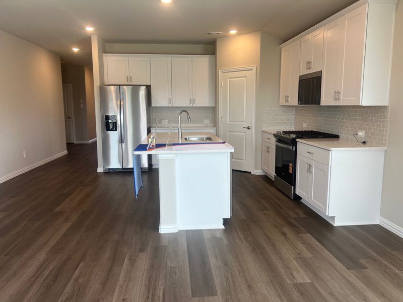 A modern kitchen with sleek white cabinets, stainless steel appliances, and dark wood flooring. A modern kitchen with sleek white cabinets, stainless steel appliances, and dark wood flooring.