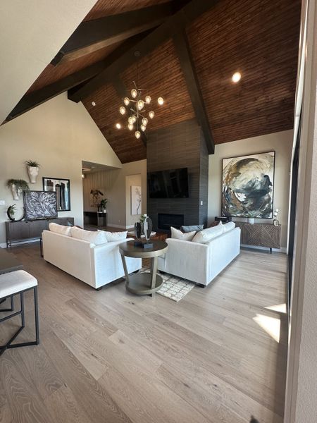 A spacious living room boasting vaulted wooden ceilings, modern lighting, and elegant art pieces for a sophisticated ambiance. A spacious living room boasting vaulted wooden ceilings, modern lighting, and elegant art pieces for a sophisticated ambiance.