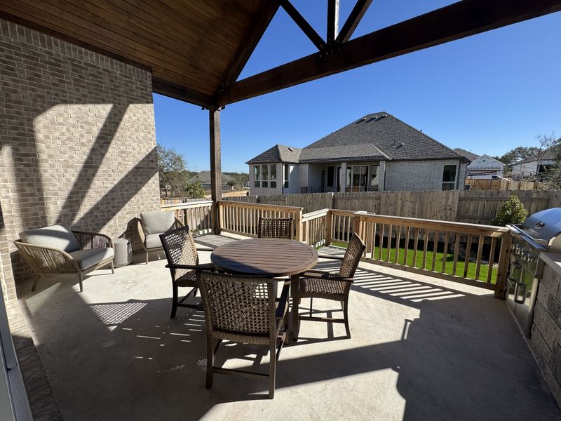 A spacious patio with cozy seating, a round table, and a grill, perfect for outdoor gatherings and relaxation.
