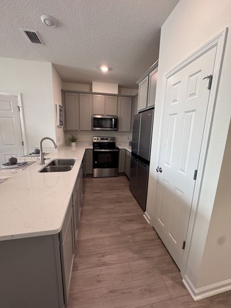 A modern kitchen featuring sleek grey cabinets, stainless steel appliances, and elegant wood flooring.