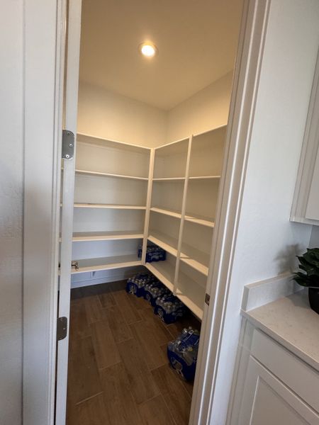 A spacious walk-in pantry with wooden flooring and ample shelving for storage.