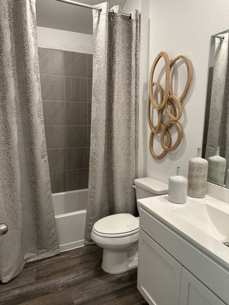Modern bathroom with elegant grey shower curtain, stylish wall art, sleek vanity, and wood-look flooring. Modern bathroom with elegant grey shower curtain, stylish wall art, sleek vanity, and wood-look flooring.
