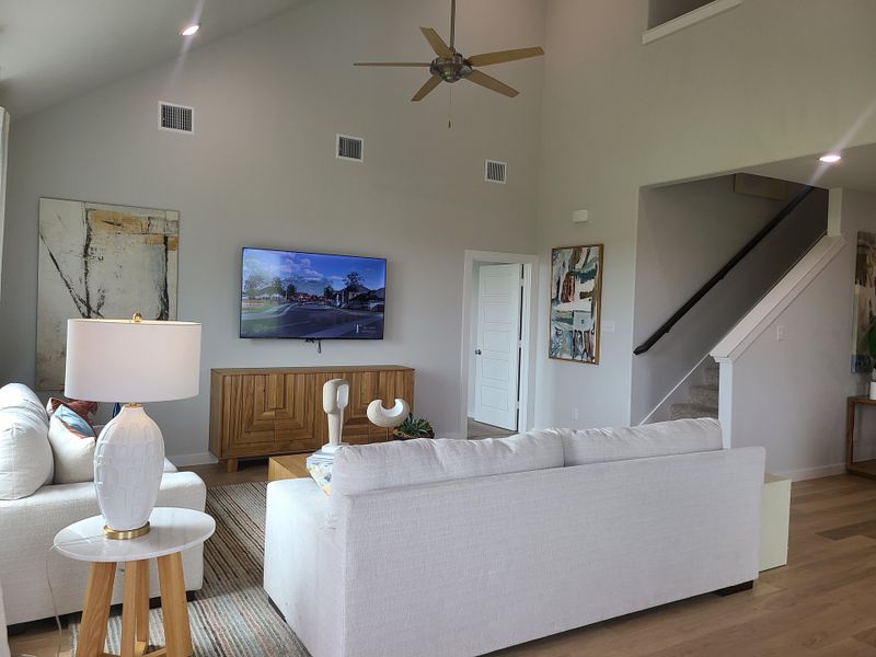 A modern living room featuring high ceilings, cozy seating, and stylish decor with warm wood accents and contemporary art.