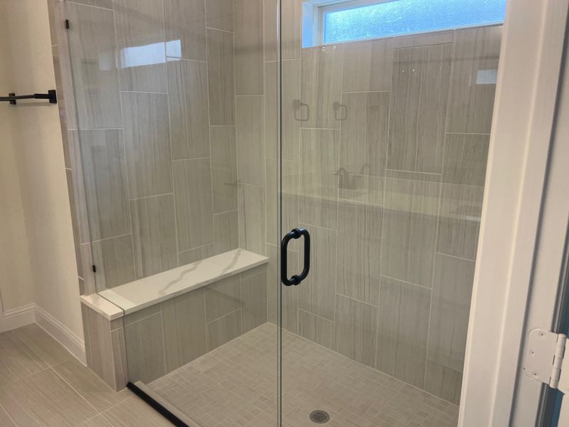 A sleek glass-enclosed shower with contemporary tiles and a built-in bench in a modern bathroom. A sleek glass-enclosed shower with contemporary tiles and a built-in bench in a modern bathroom.