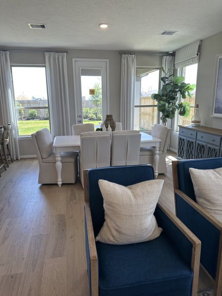 A bright dining area with elegant seating, natural light, and hardwood floors, featuring a chic decor and garden view.