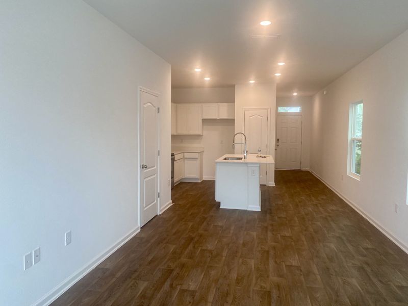 A modern kitchen space with an island sink, wood-style flooring, and recessed lighting. A modern kitchen space with an island sink, wood-style flooring, and recessed lighting.