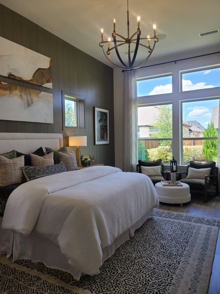 A cozy bedroom featuring a plush bed, elegant chandelier, and large windows with a view to the outdoors. A cozy bedroom featuring a plush bed, elegant chandelier, and large windows with a view to the outdoors.